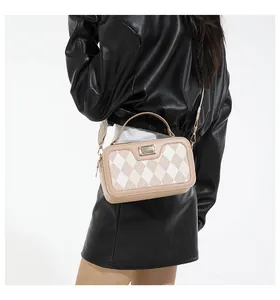 Detail of pink plaid quilted handbag showing the gold logo plate and PU leather texture
