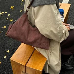 Deep brown suede shoulder bag shown with beige trench coat in an autumn outdoor setting
