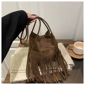 Détail d'un sac seau en daim marron avec de longues franges et un style bohème