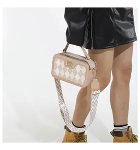 Detailed view of argyle patterned crossbody bag with gold plaque and wide strap