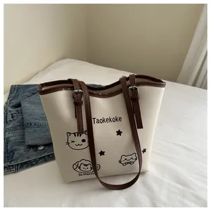 Detail view of the tote bag showing the cartoon cat print and adjustable leather strap