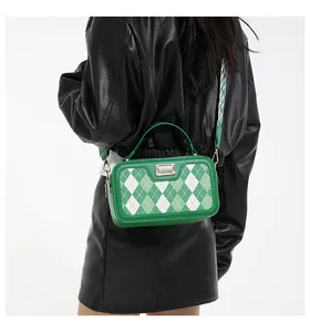 Detail of green and white checkered handbag with wide strap shown on a model