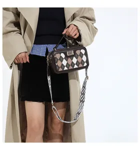 Detail of checkered crossbody bag showing dual zipper design and geometric strap texture