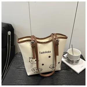 Detail of white bucket bag with brown leather trim, cat print and silver buckle