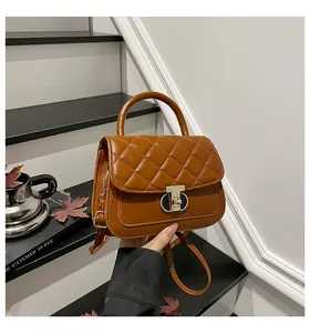 Macro detail van de gewatteerde crossbodytas in karamel met gouden T-sluiting en handvat