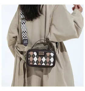 Detail of checkered crossbody bag with wide strap worn by model in beige trench coat