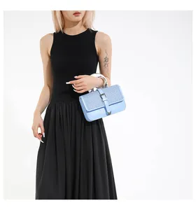 Détail du sac bandoulière bleu clair avec rabat tissé et poignée en métal argenté