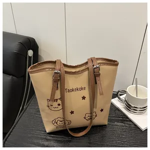 Detail of a cream bucket bag showing a cartoon cat illustration and adjustable brown straps