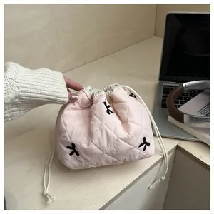 Detailed view of pink quilted drawstring pouch with bow embroidery for organization