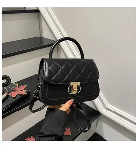 Detail van zwarte gewatteerde handtas met goudkleurig slot en elegant handvat bovenaan