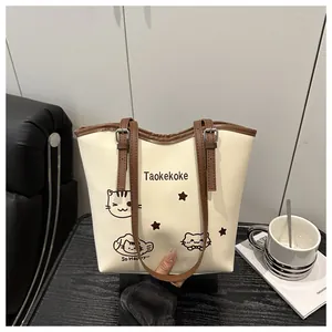 Detail of cream bucket bag with cat print and adjustable brown shoulder strap