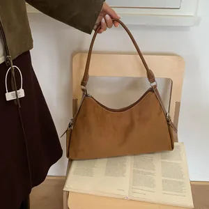 Detail of vintage brown suede shoulder bag featuring contrast stitching on leather straps