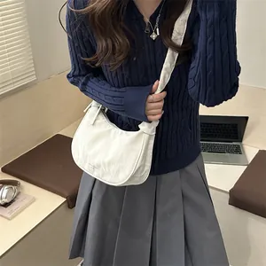 Pleated white crescent crossbody bag with bow detail and brand logo on nylon fabric