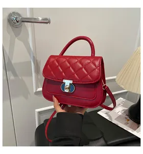 Detail van rode gewatteerde handtas met elegante gouden draaisluiting en handvat