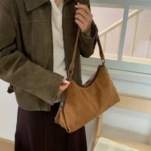 Detail of brown suede hobo bag featuring contrast white stitching and premium texture