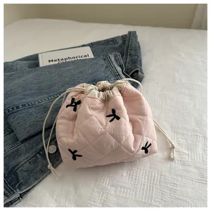 Detail of pink quilted drawstring pouch with black embroidered ribbon bows and soft texture