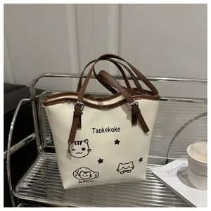 Detail of adjustable shoulder strap and cute cat illustrations on cream bucket bag