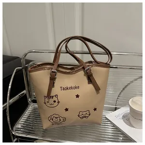 Detail of beige tote bag with cute cartoon cats and brown strap on metal rack