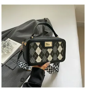 Detail of checkered plaid handbag with gold logo plate and wide wave pattern shoulder strap