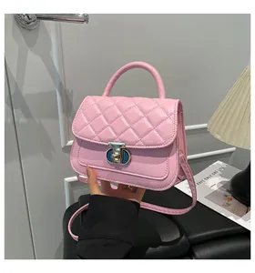 Detailweergave van roze gewatteerde tas met decoratieve goudkleurige draaisluiting en handvat