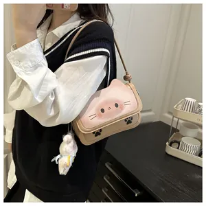 Détail d'un sac bandoulière chat beige avec rabat rose et pendentif en peluche doux