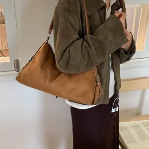 Detail of dark brown matte leather shoulder bag with silver buckle on green suede coat