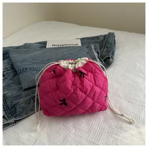 Detail of rose red quilted drawstring bag with black bow embroidery and white rope closure