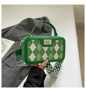 Detail of green argyle crossbody bag with wide wavy shoulder strap and gold hardware