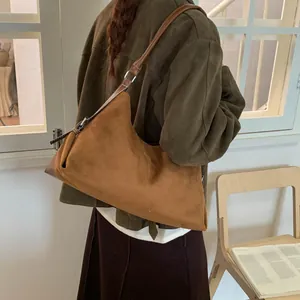 Detailed texture of brown suede crescent bag with silver metallic buckle and strap