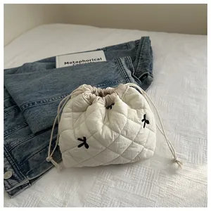 Detail of white quilted drawstring pouch with delicate black embroidered bows