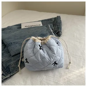 Macro shot of light blue quilted drawstring bag with bow embroidery and beige lining