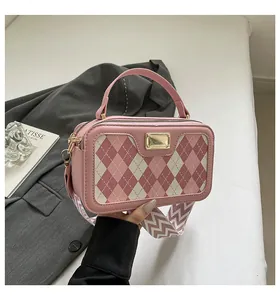 Detail of pink plaid handbag with wide patterned strap and golden metal hardware