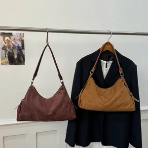 Detailed view of dark brown and yellow suede shoulder bags on elegant hangers