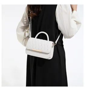 Detail of white quilted handbag with wavy stitching and sleek gold metal clasp hardware