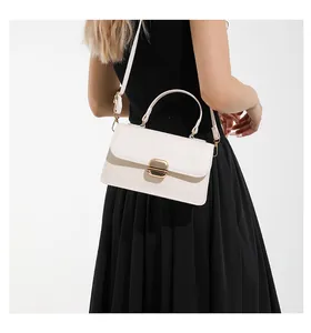 Close-up of minimalist cream white square handbag with golden buckle on black dress