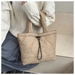Detail of heart quilting and drawstring closure on beige puffy bucket handbag