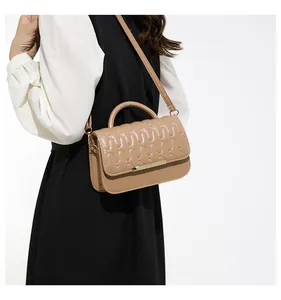 Detail of khaki crossbody bag featuring wavy quilted stitching and gold metal trim