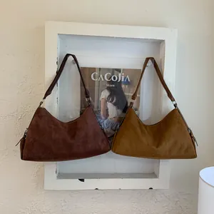 Detailed close-up of dark brown and caramel suede hobo bags hanging on a minimal frame