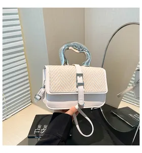 Détail du sac bicolore avec poignée en métal argenté et texture en paille tressée
