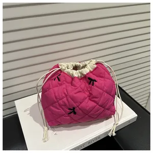Close-up of quilted rose red drawstring pouch with bow embroidery on a white book