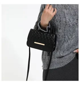 Detail of black crossbody bag with quilted wave pattern and gold metal buckle on model