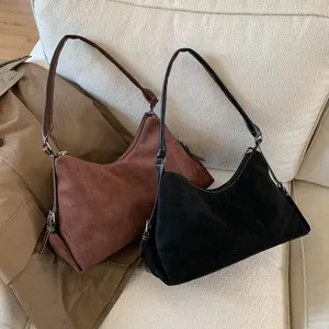 Detail of minimalist hobo bags in black and brown suede with contrast white stitching