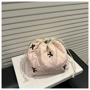 Detailed close-up of light pink quilted drawstring pouch with black bow embroidery