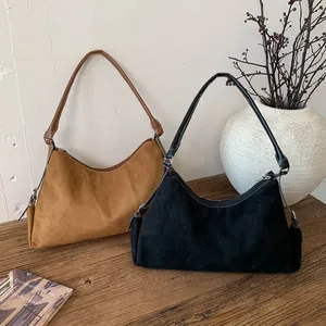 Detail of vintage suede underarm bags in brown and black on a rustic wooden stand