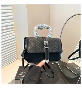 Détail du sac en cuir noir avec poignée métallique argentée et texture tissée