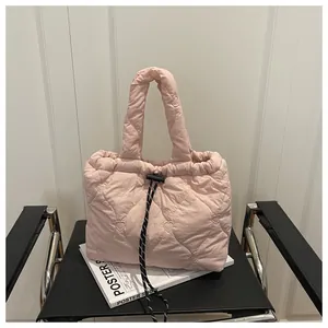 Close-up of pink quilted dumpling bag with heart embroidery and black drawstring closure