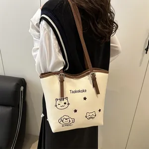 Chic cream bucket bag with brown trim and cute cat prints shown on model back shoulder