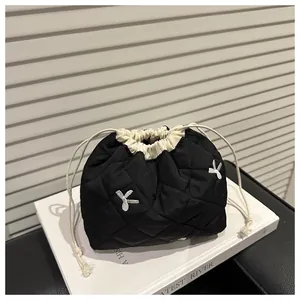 Detail of black quilted drawstring pouch with contrast lining and white bow embroidery