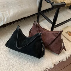Detailed shot of crescent shoulder bag with white stitching in black and brown suede