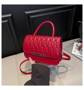 Detail of red wave quilted handbag with gold metal bar and cylinder handle